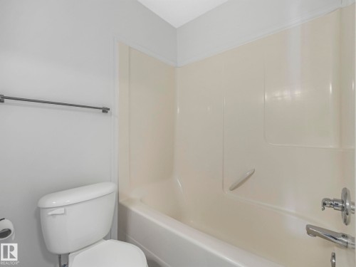 Bathroom featuring a white toilet, a grey towel bar, and a bathtub with a shower kit - 14 15128 22 Street, Edmonton, AB - Indoor Photo Showing Bathroom