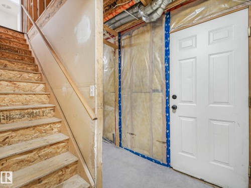 The property features unfinished wooden stairs with a wooden handrail, leading to additional areas - 14 15128 22 Street, Edmonton, AB - Indoor