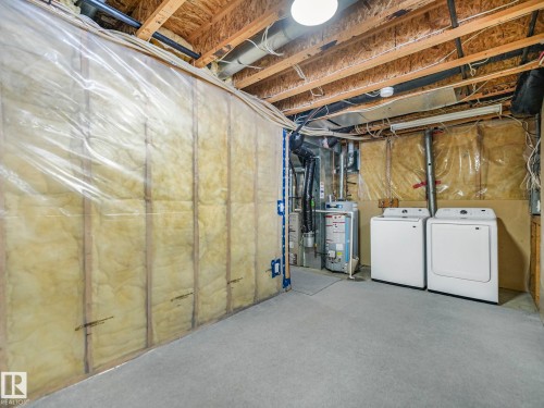 The utility area features a clothes washer and dryer, a water heater, and exposed ceiling joists - 14 15128 22 Street, Edmonton, AB - Indoor Photo Showing Laundry Room
