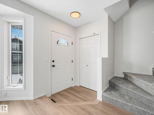 Entryway featuring light-toned flooring, a bright white door with an arched window, and a carpeted staircase - 14 15128 22 Street, Edmonton, AB - Indoor Photo Showing Other Room