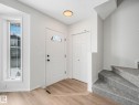 Entryway featuring light-toned flooring, a bright white door with an arched window, and a carpeted staircase - 14 15128 22 Street, Edmonton, AB  - Indoor Photo Showing Other Room 