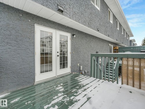 The property features a private deck with a railing, accessible via white French doors with glass panes - 14 15128 22 Street, Edmonton, AB - Outdoor With Deck Patio Veranda
