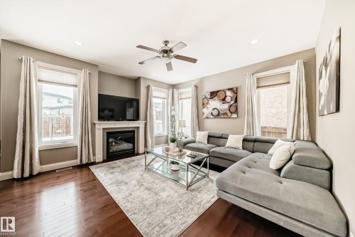 This living area features hardwood floors and a fireplace with a white mantel - 3220 151 Avenue, Edmonton, AB - Indoor Photo Showing Living Room With Fireplace