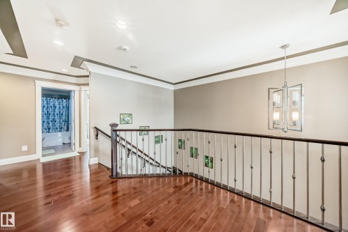 The property features rich hardwood flooring, a staircase with a wrought iron railing, and a modern chandelier - 3220 151 Avenue, Edmonton, AB - Indoor Photo Showing Other Room