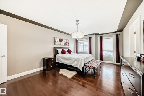 This bedroom features rich hardwood flooring, light neutral walls, and a tray ceiling - 3220 151 Avenue, Edmonton, AB - Indoor Photo Showing Bedroom