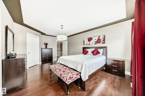 This room features hardwood flooring, a recessed ceiling with accent trim, and a decorative chandelier - 3220 151 Avenue, Edmonton, AB - Indoor Photo Showing Bedroom