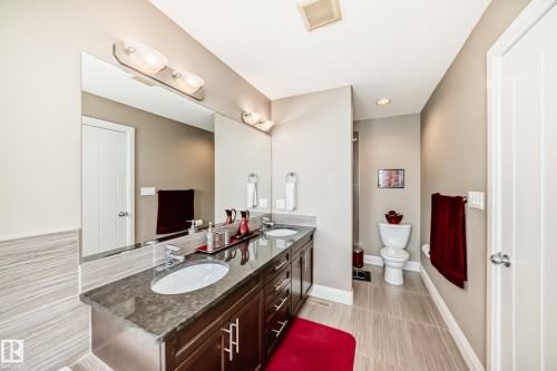 Bathroom featuring a dual vanity with a dark wood cabinet, a large mirror, and recessed lighting - 3220 151 Avenue, Edmonton, AB - Indoor Photo Showing Bathroom