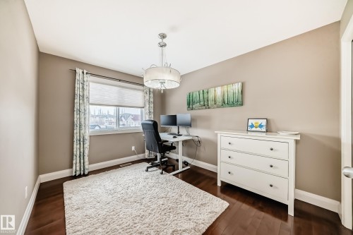 This versatile room features hardwood floors, a large window with blinds and patterned curtains, and a contemporary chandelier - 3220 151 Avenue, Edmonton, AB - Indoor Photo Showing Office