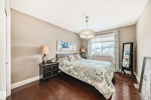 Bedroom featuring dark hardwood flooring, a window with blinds and patterned curtains, and a chandelier with a drum shade - 3220 151 Avenue, Edmonton, AB - Indoor Photo Showing Bedroom
