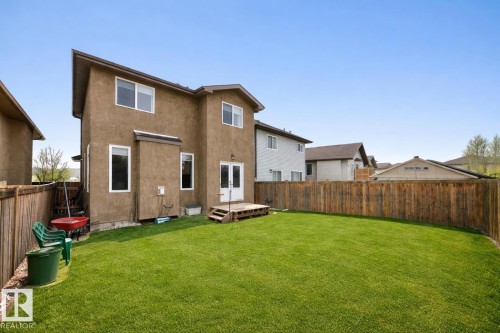 The property features a spacious backyard with a well-maintained lawn, enclosed by a wooden fence - 3220 151 Avenue, Edmonton, AB - Outdoor With Exterior