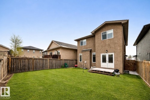 The property features a spacious backyard with a well-maintained lawn and a wooden fence - 3220 151 Avenue, Edmonton, AB - Outdoor With Exterior