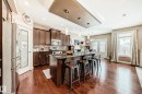 This bright kitchen features hardwood flooring, dark wood cabinetry, and stainless steel appliances - 3220 151 Avenue, Edmonton, AB  - Indoor Photo Showing Kitchen With Upgraded Kitchen 
