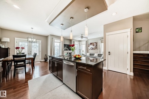 Open concept living space featuring hardwood floors, a kitchen island with pendant lighting, and a dining area with French doors - 3220 151 Avenue, Edmonton, AB - Indoor Photo Showing Kitchen With Upgraded Kitchen