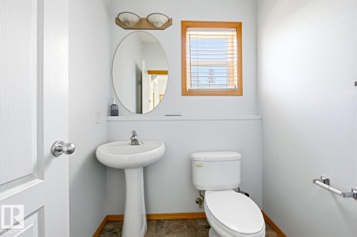 Bathroom featuring a pedestal sink, white toilet, and wood-finish flooring - 9904 144 Avenue, Edmonton, AB - Indoor Photo Showing Bathroom