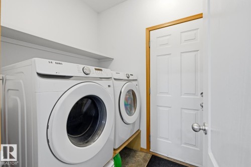 Dedicated laundry area featuring a built-in shelf, white walls, and wood-finish trim - 9904 144 Avenue, Edmonton, AB - Indoor Photo Showing Laundry Room
