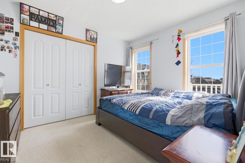 Bright room featuring two large windows, light-colored carpeting, and a double-door closet with wood trim - 9904 144 Avenue, Edmonton, AB - Indoor Photo Showing Bedroom