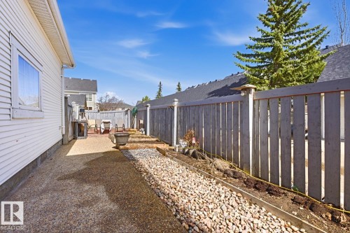 Side yard featuring a concrete path, gravel landscaping, and a privacy fence - 9904 144 Avenue, Edmonton, AB - Outdoor With Exterior
