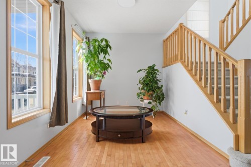 Living area featuring wood-finish flooring, white walls, and a prominent staircase with natural wood railings and carpeted treads - 9904 144 Avenue, Edmonton, AB - Indoor Photo Showing Other Room