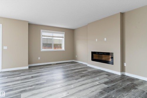 Spacious interior featuring wood-finish flooring, a built-in electric fireplace, and neutral wall tones - 3314 9 Street Nw, Edmonton, AB - Indoor Photo Showing Living Room With Fireplace