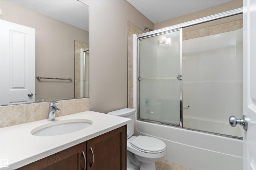 Bathroom featuring a dark wood vanity with a white countertop, undermount sink, and chrome faucet - 3314 9 Street Nw, Edmonton, AB - Indoor Photo Showing Bathroom