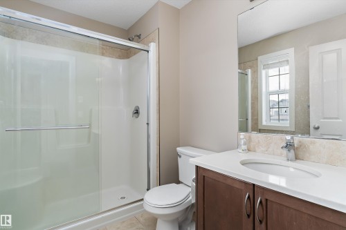 Shower with sliding glass enclosure, a vanity with a white countertop and undermount sink, and a large mirror - 3314 9 Street Nw, Edmonton, AB - Indoor Photo Showing Bathroom