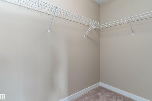 Walk-in closet featuring wire shelving, beige wall paint, white baseboards, and carpet flooring - 3314 9 Street Nw, Edmonton, AB - Indoor With Storage