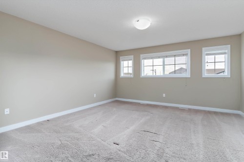 Neutral tone wall paint, light-colored carpet flooring, white trim, multiple windows, and a flush mount ceiling light - 3314 9 Street Nw, Edmonton, AB - Indoor Photo Showing Other Room