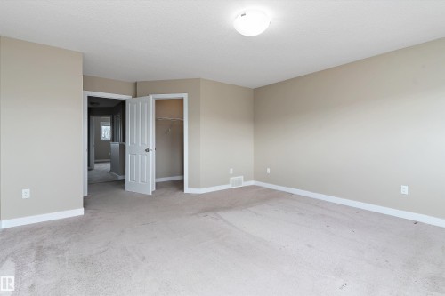 Carpeted room featuring neutral wall paint, white baseboards, and a flush-mount ceiling light fixture - 3314 9 Street Nw, Edmonton, AB - Indoor Photo Showing Other Room