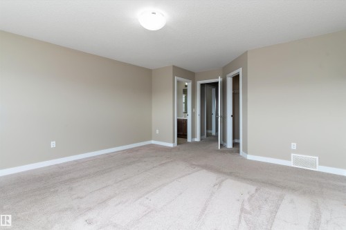 Spacious room featuring neutral carpeting, light beige walls, white trim, a flush mount ceiling light, and multiple doorways - 3314 9 Street Nw, Edmonton, AB - Indoor Photo Showing Other Room