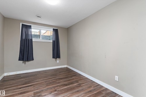 Warm-toned wood-finish flooring complements neutral wall tones - 3314 9 Street Nw, Edmonton, AB - Indoor Photo Showing Other Room