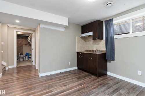 Wood-finish flooring throughout a versatile space featuring a compact kitchenette - 3314 9 Street Nw, Edmonton, AB - Indoor