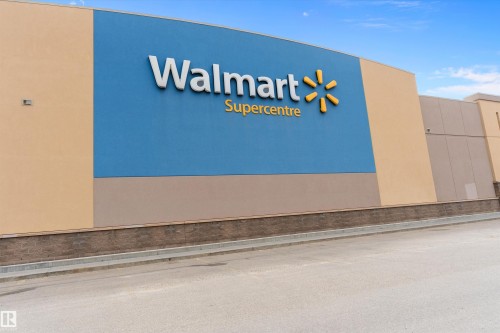 Commercial property featuring a large blue facade with prominent signage, complemented by neutral-toned stucco and a dark stone-finish base - 3314 9 Street Nw, Edmonton, AB - 