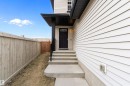 Exterior entrance featuring a black paneled door with window inserts, concrete steps, a covered porch with dark soffit, and light-colored siding - 3314 9 Street Nw, Edmonton, AB  - Outdoor 