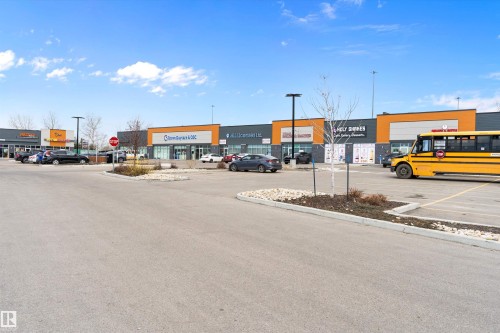 Retail plaza with multiple storefronts featuring contemporary architecture, ample parking, landscaping elements, and modern exterior lighting - 3314 9 Street Nw, Edmonton, AB - Outdoor