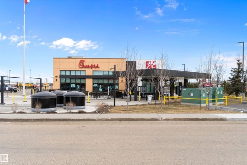 Contemporary commercial building featuring a light-colored facade with dark-framed windows, a drive-thru canopy, and exterior signage - 3314 9 Street Nw, Edmonton, AB - Outdoor