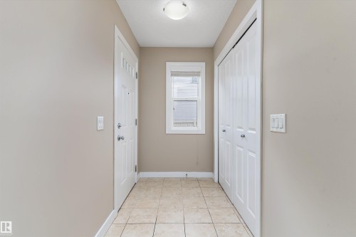 Entryway featuring neutral wall paint, tiled flooring, a window with blinds, a front door with decorative glass inserts, and a bifold closet door - 3314 9 Street Nw, Edmonton, AB - Indoor Photo Showing Other Room