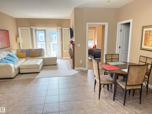 This property features a dining area with tiled flooring, leading to a carpeted living space - 438 1406 Hodgson Way, Edmonton, AB - Indoor