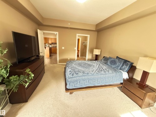 This room features light-colored carpeting, warm-toned walls, and a dropped ceiling with recessed lighting - 438 1406 Hodgson Way, Edmonton, AB - Indoor Photo Showing Bedroom