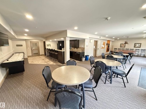 This communal area features carpeted flooring, recessed lighting, and a variety of seating arrangements including round tables with chairs - 438 1406 Hodgson Way, Edmonton, AB - Indoor Photo Showing Dining Room