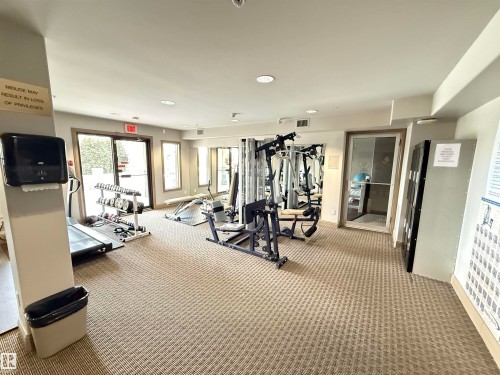 The property features a dedicated fitness area with various exercise equipment, including a treadmill and weight machines - 438 1406 Hodgson Way, Edmonton, AB - Indoor Photo Showing Gym Room