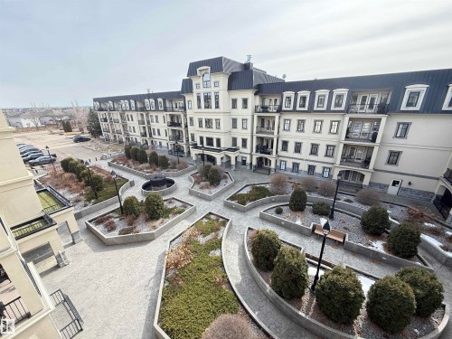 The property features exterior architecture with dormer windows and balconies, and a well-maintained courtyard with pathways, landscaping, and a central water feature - 438 1406 Hodgson Way, Edmonton, AB - Outdoor