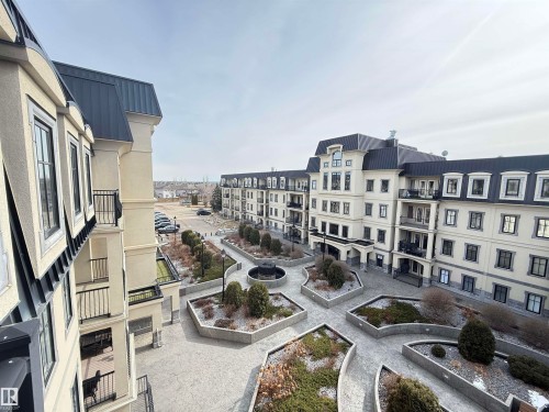 The property offers exterior balconies with dark railings, providing views of the surrounding buildings and landscaped courtyard - 438 1406 Hodgson Way, Edmonton, AB - Outdoor