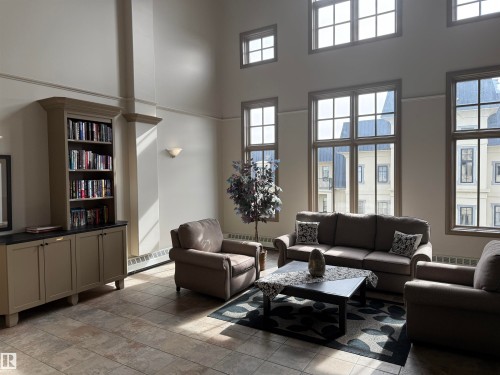 This inviting common area features high ceilings, tile flooring, and multiple windows allowing for abundant natural light - 438 1406 Hodgson Way, Edmonton, AB - Indoor Photo Showing Living Room