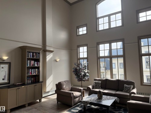 This Lobby space features high ceilings, large windows, and wall sconces - 438 1406 Hodgson Way, Edmonton, AB - Indoor Photo Showing Living Room
