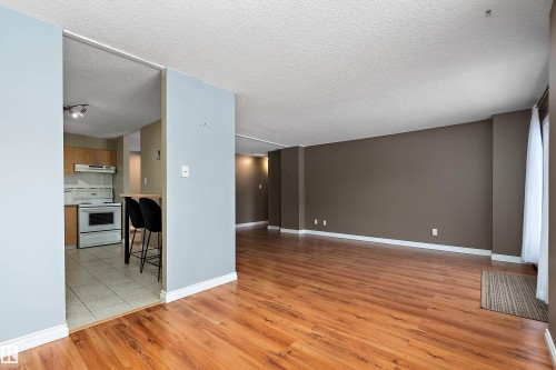 Spacious living area featuring wood-finish flooring and neutral wall tones - 206 9929 113 Street, Edmonton, AB - Indoor Photo Showing Other Room
