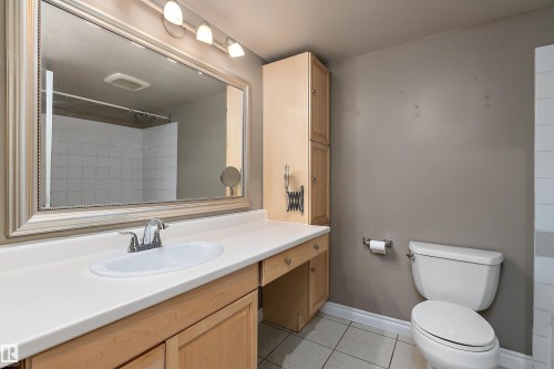 Bathroom featuring a spacious vanity with an integrated sink, ample counter space, and light wood-finish cabinetry - 206 9929 113 Street, Edmonton, AB - Indoor Photo Showing Bathroom