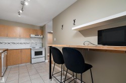 Kitchen featuring wood-finish cabinetry, tile flooring, white appliances, and a breakfast bar with an integrated floating shelf - 