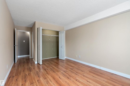 Spacious bedroom featuring neutral-toned walls, and a large bi-fold closet with interior shelving - 206 9929 113 Street, Edmonton, AB - Indoor Photo Showing Other Room