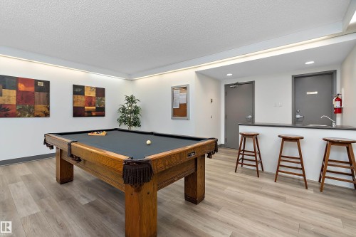 Recreation room with wood-finish flooring and a built-in bar area - 206 9929 113 Street, Edmonton, AB - Indoor Photo Showing Other Room