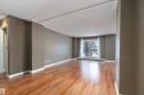 Spacious living area featuring warm wood-finish flooring, neutral wall tones, and white baseboards - 206 9929 113 Street, Edmonton, AB  - Indoor Photo Showing Other Room 